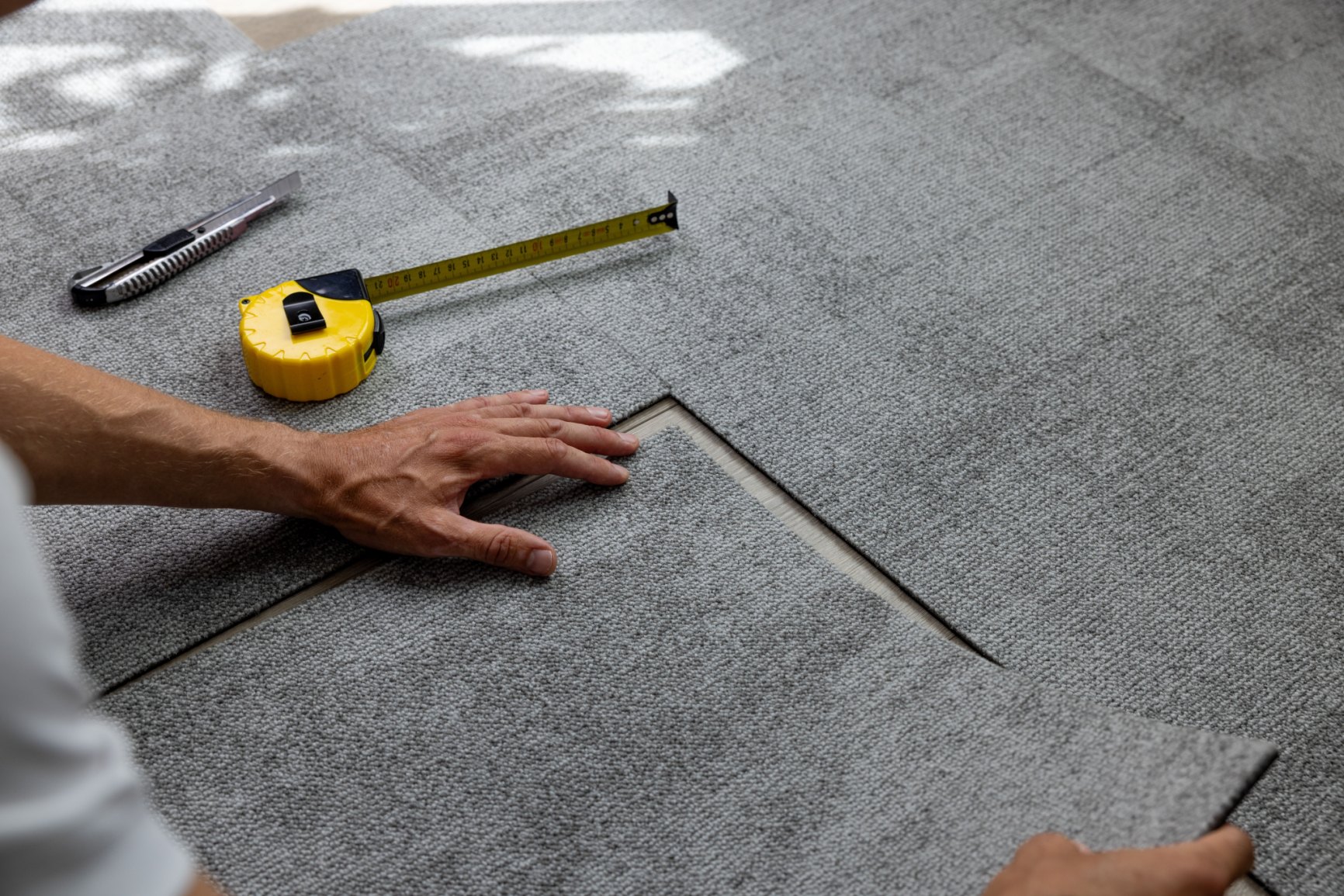 A tape measure pulled across a bare subfloor before a new floor is laid.