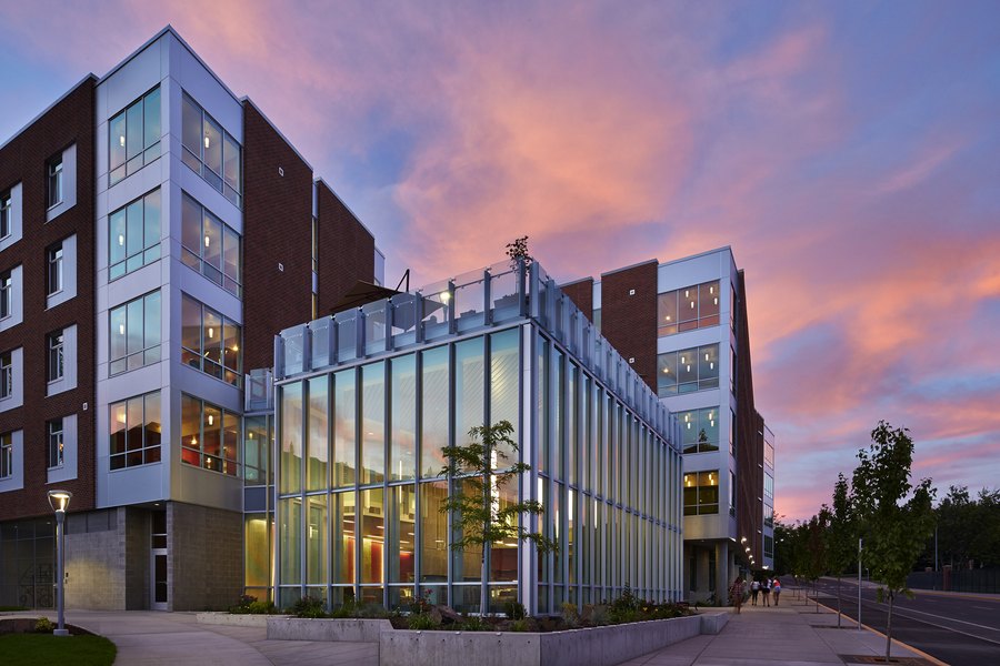 A newly built commercial block, glass frontage lit against an evening sky.